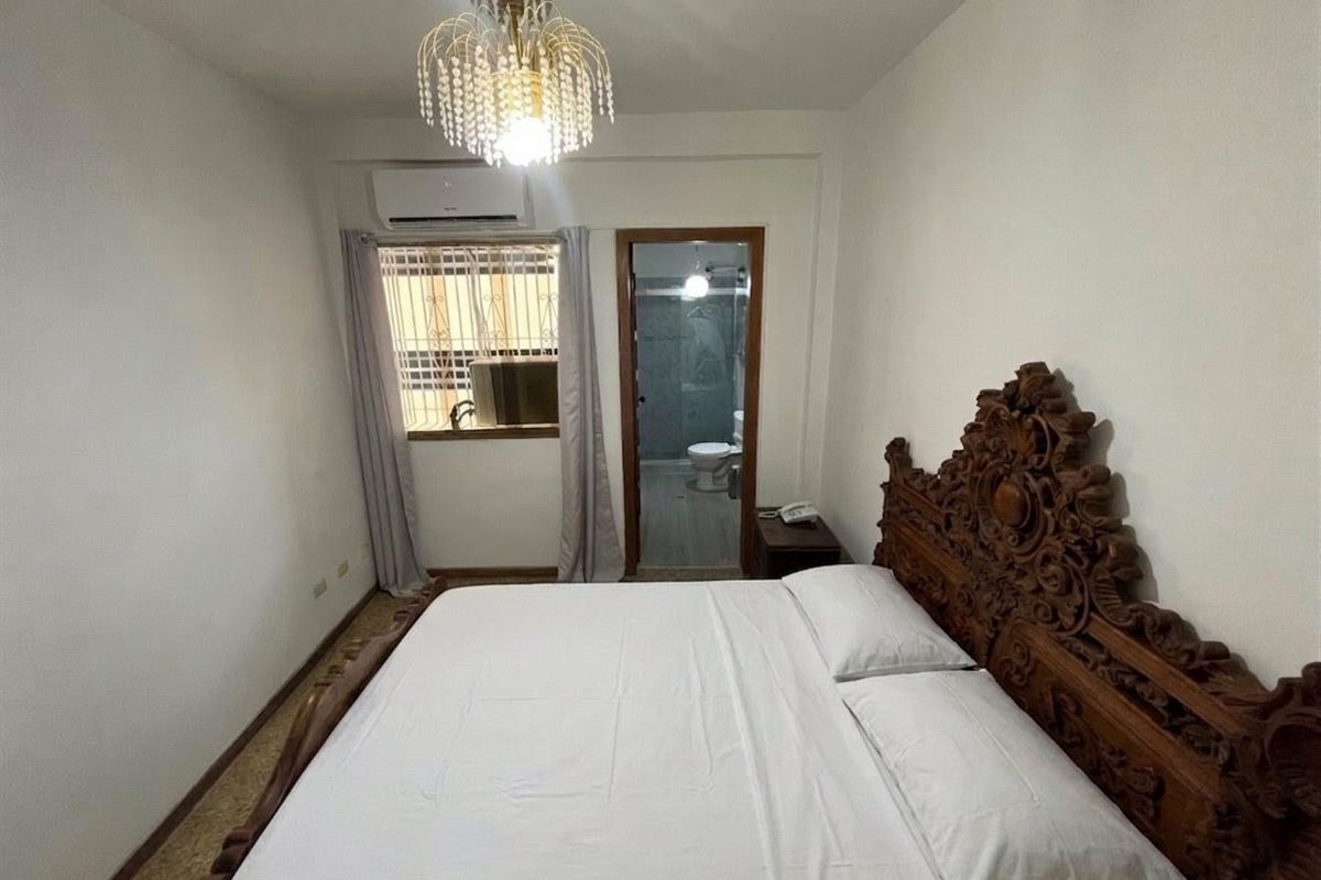 Habitación con cabecera de madera tallada
