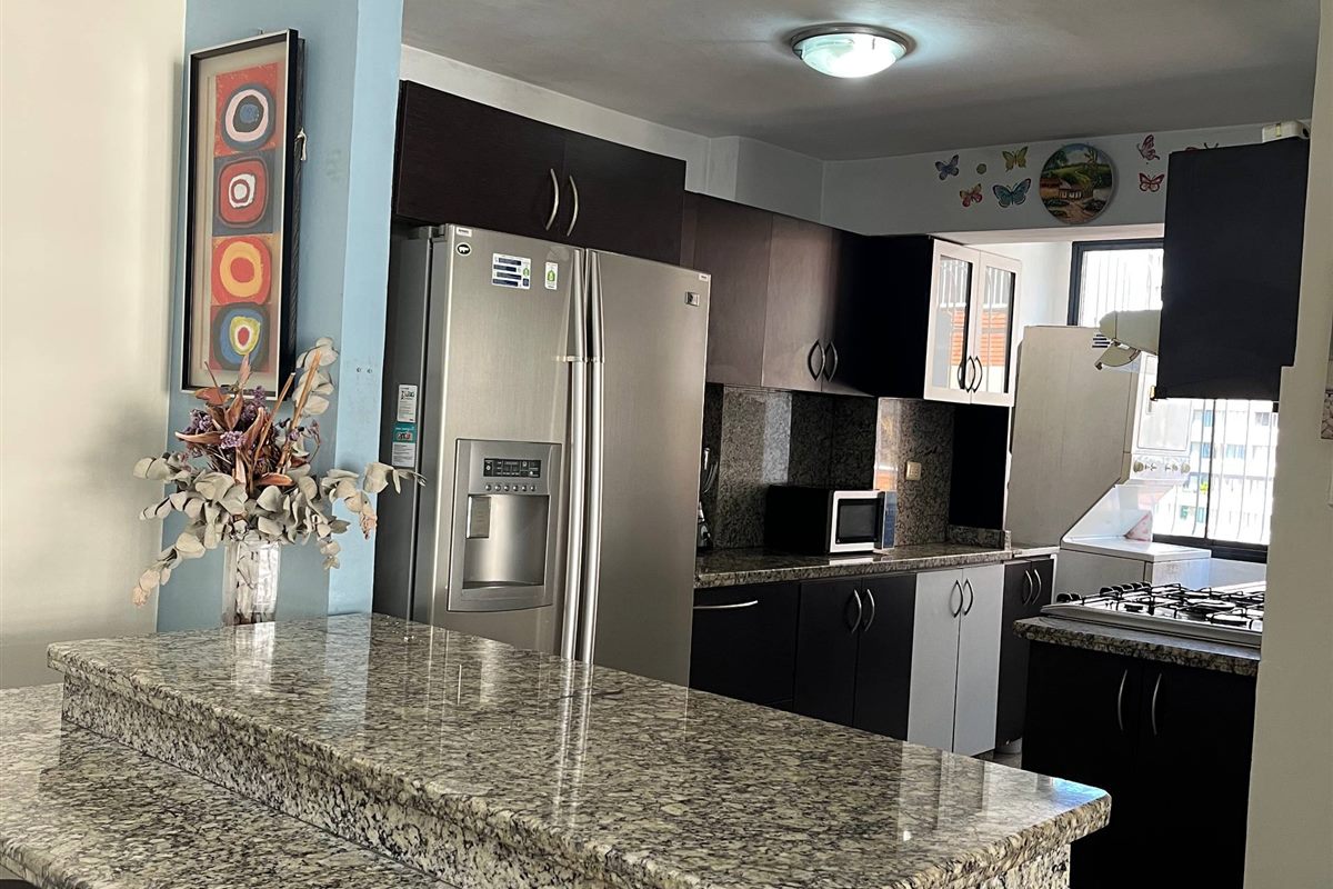 Cocina con isla de granito y barra en Residencias Terepaima
